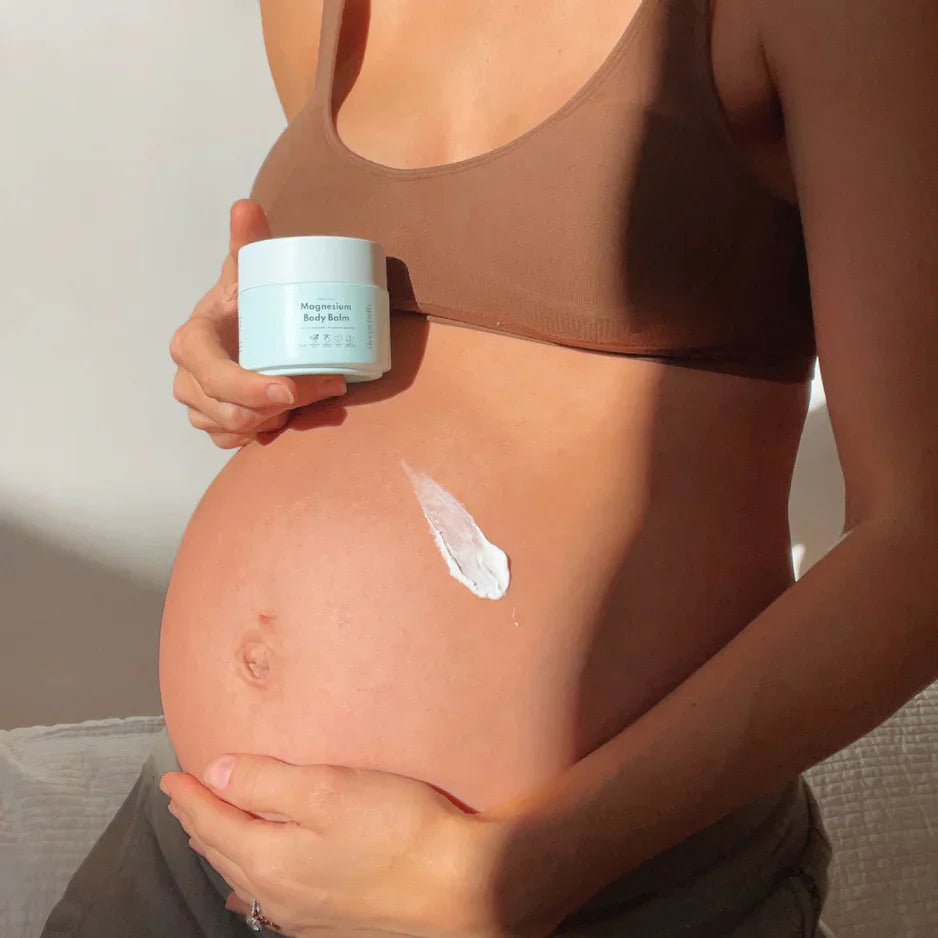 pregnant women holding magnesium body balm in her hand